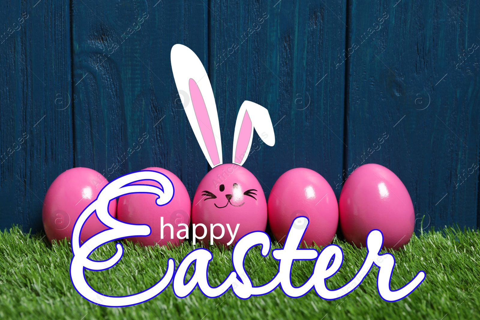 Image of Happy Easter. One egg with drawn face and ears as bunny among others on green grass against blue wooden background