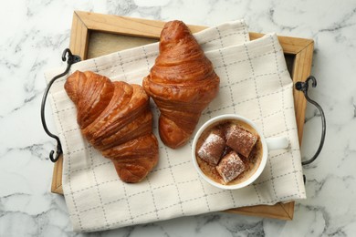 Tasty croissants served with cup of hot drink on white marble table, top view