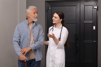 Young healthcare worker assisting senior man indoors