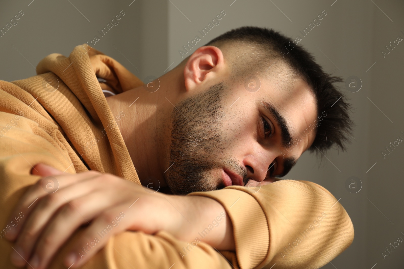 Photo of Sad young man in hoodie at home