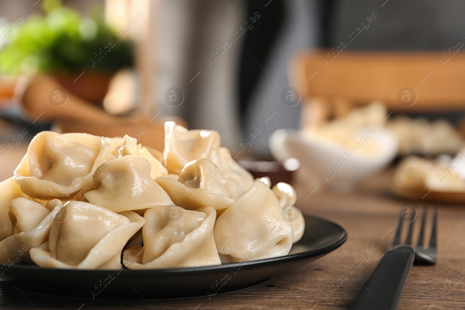 Photo of Tasty dumplings with butter on wooden table against blurred background