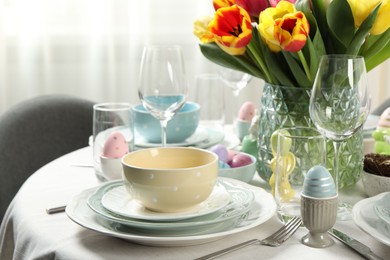 Photo of Easter celebration. Festive table setting with beautiful flowers and painted eggs