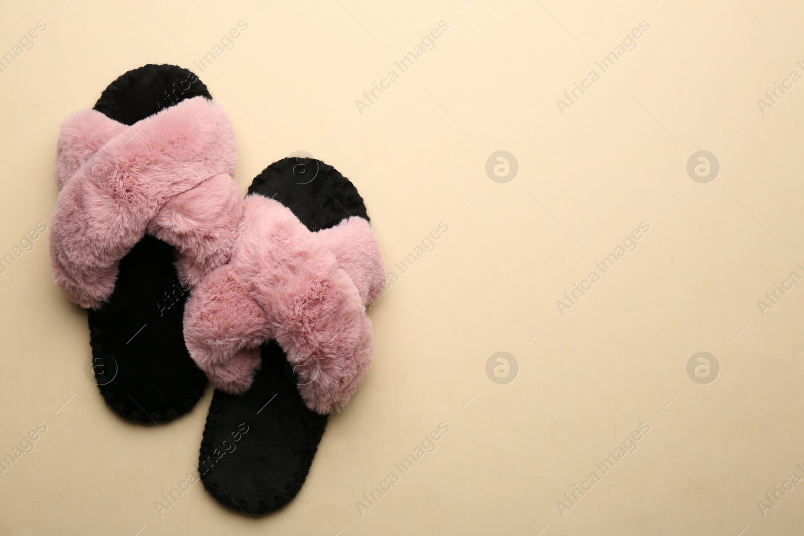 Photo of Pair of soft slippers on beige background, flat lay. Space for text