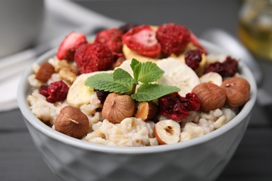 Photo of Oatmeal with freeze dried fruits, nuts and mint in bowl, closeup