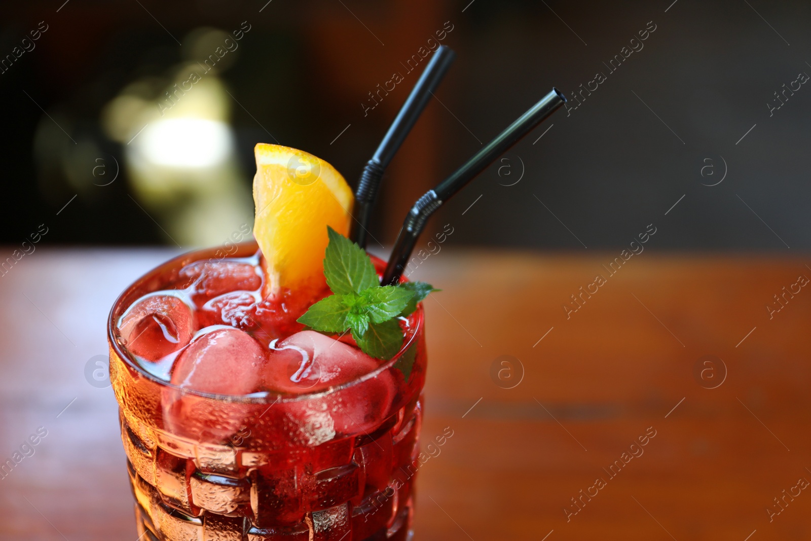 Photo of Glass of delicious cocktail with ice on table, closeup