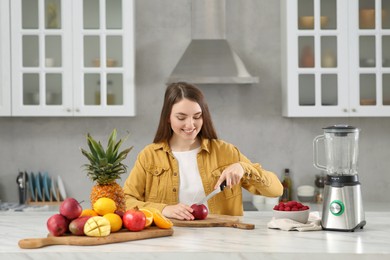 Woman preparing ingredients for tasty smoothie at white marble table in kitchen