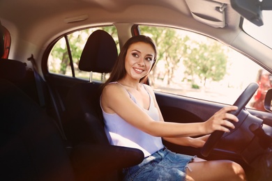 Happy young beautiful woman driving modern car