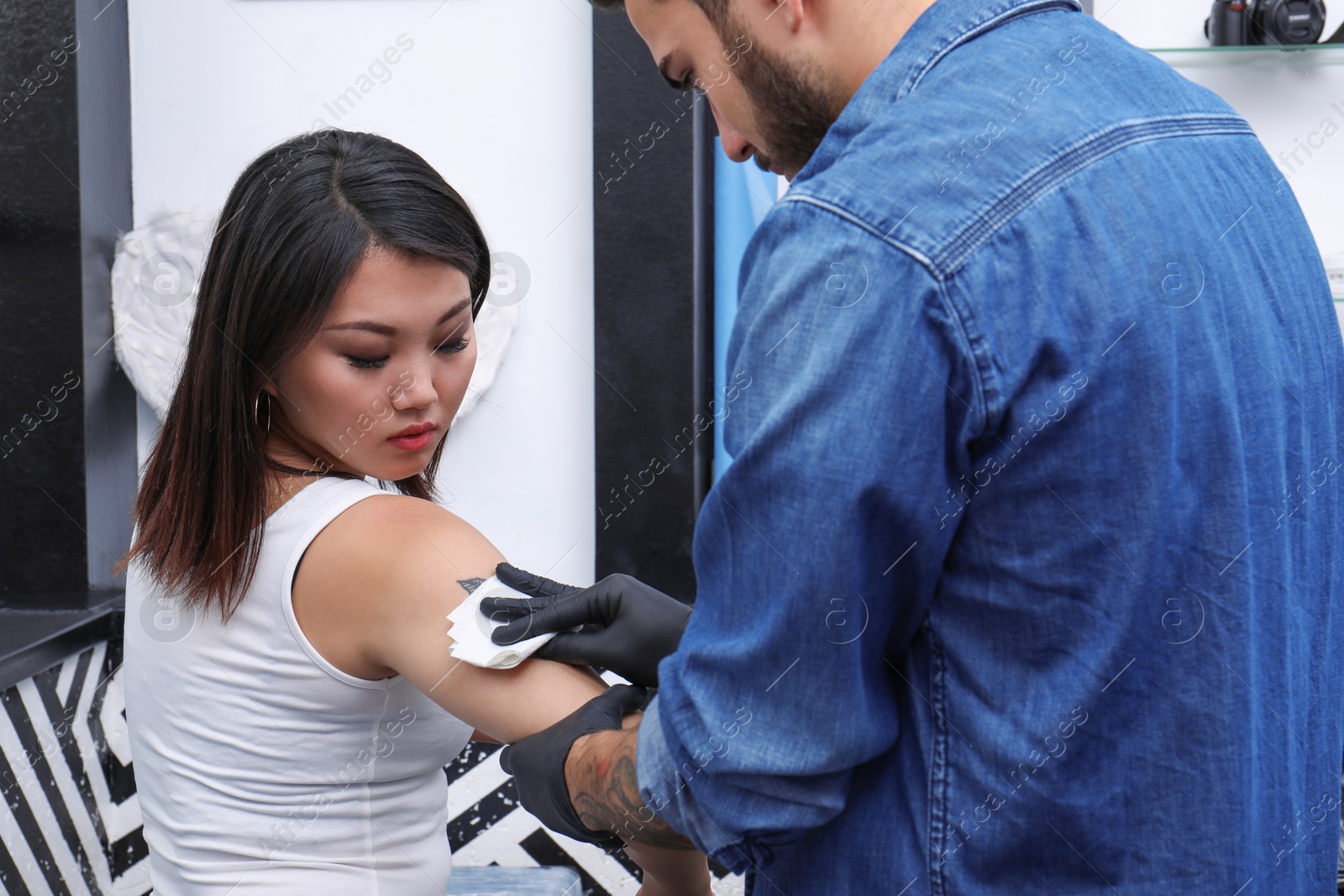 Photo of Professional artist making stylish tattoo in salon