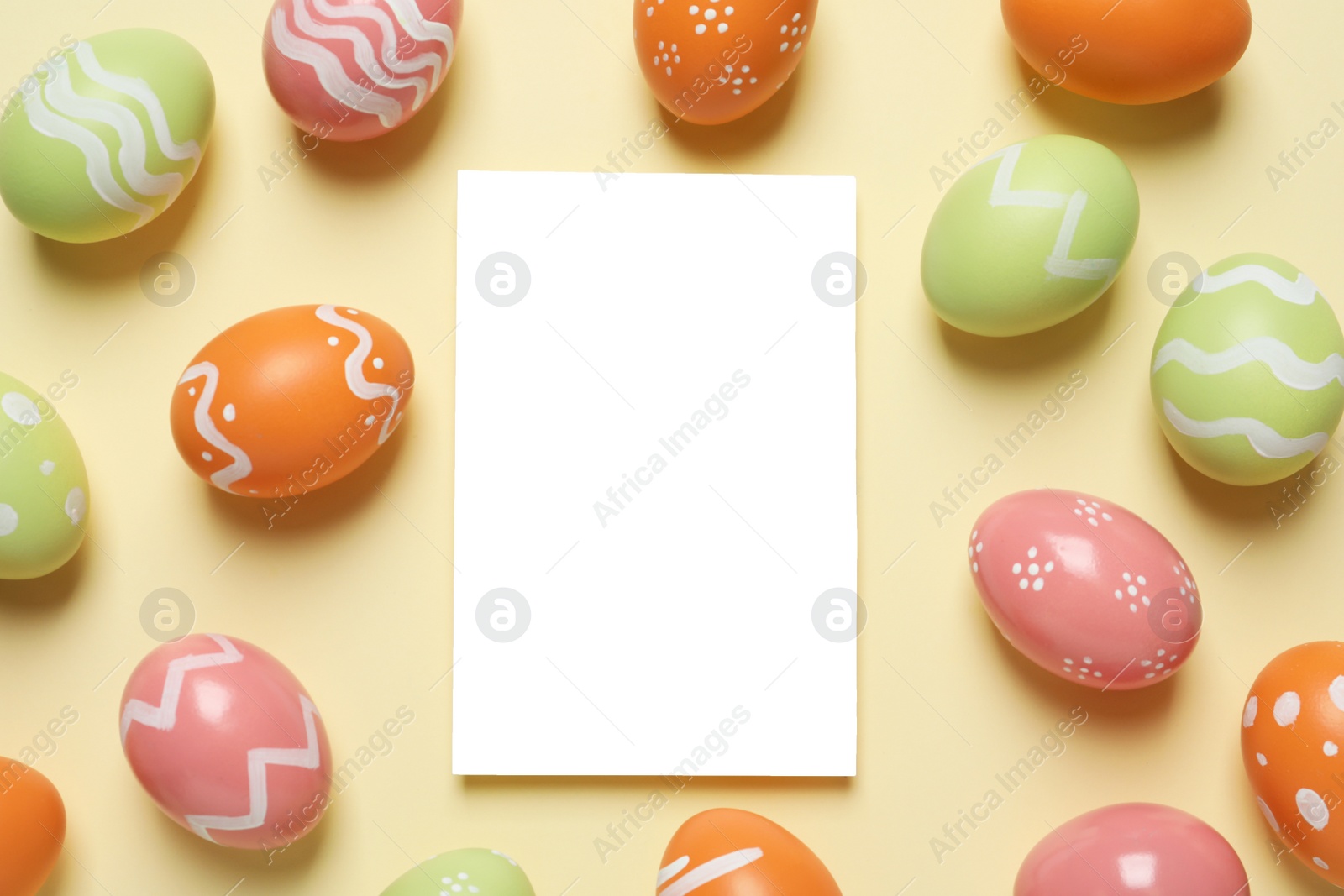 Photo of Flat lay composition of painted Easter eggs and blank card on color background, space for text