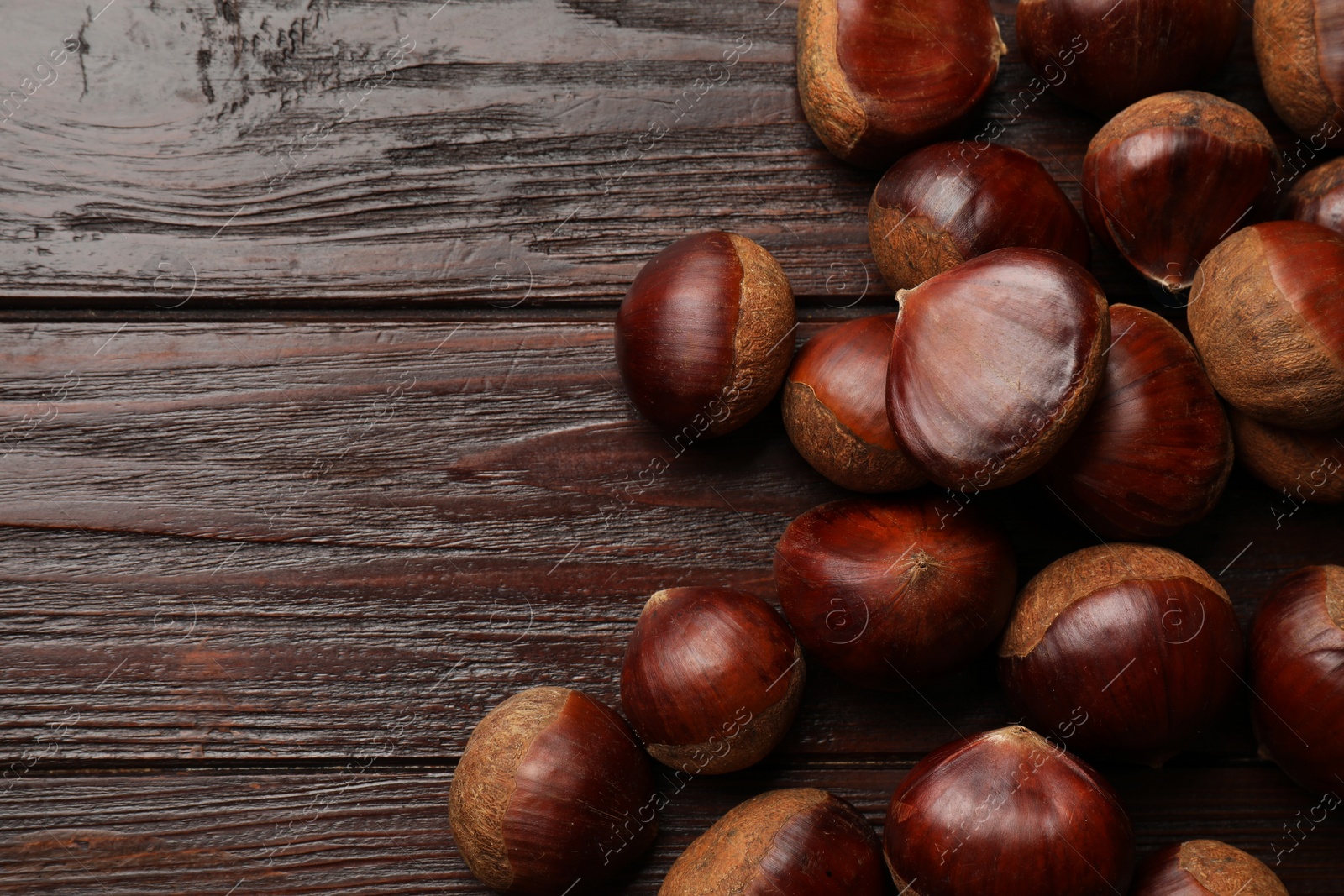 Photo of Sweet fresh edible chestnuts on wooden table, top view. Space for text