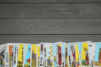 Photo of Tarot cards on grey wooden table, top view. Space for text