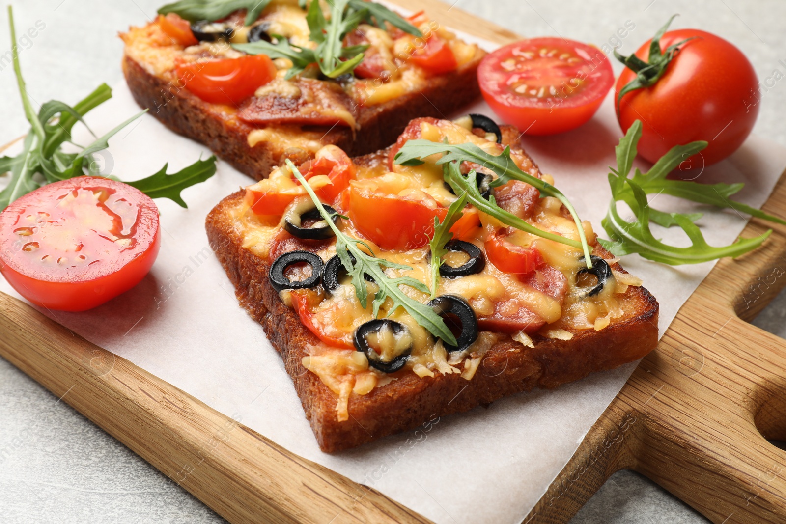Photo of Tasty pizza toasts, fresh tomatoes and parsley on grey table, closeup