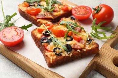 Photo of Tasty pizza toasts, fresh tomatoes and parsley on grey table, closeup