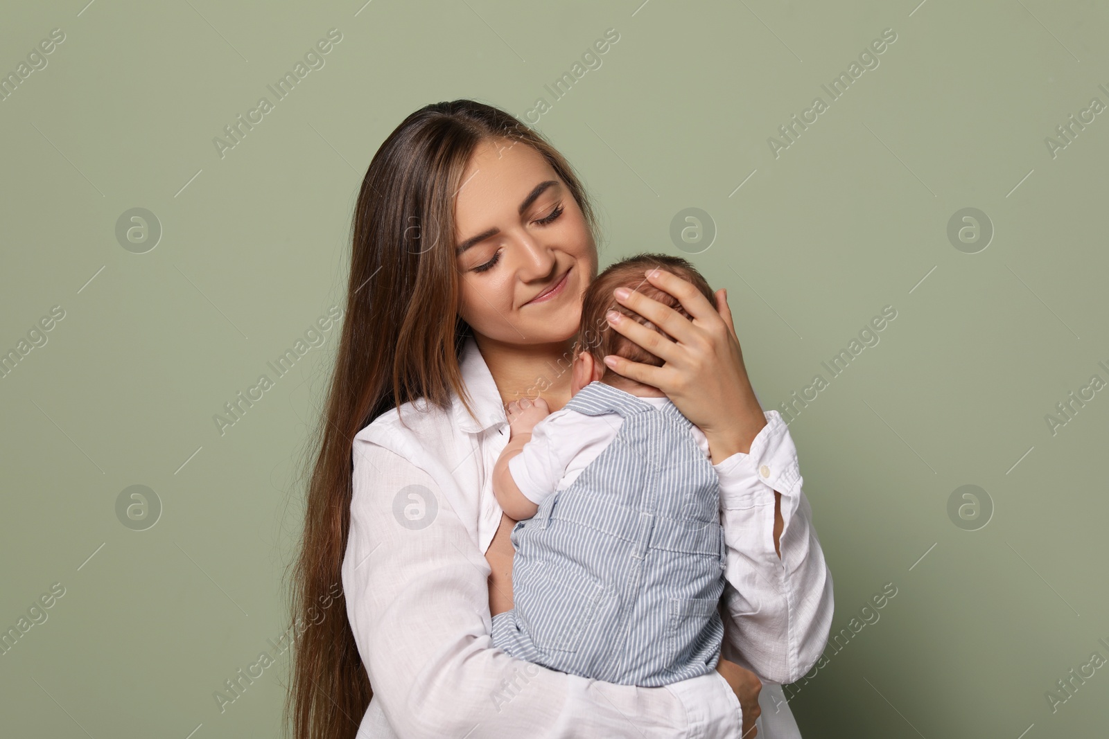 Photo of Mother holding her cute newborn baby on olive background