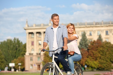 Happy couple riding bicycle outdoors on sunny day