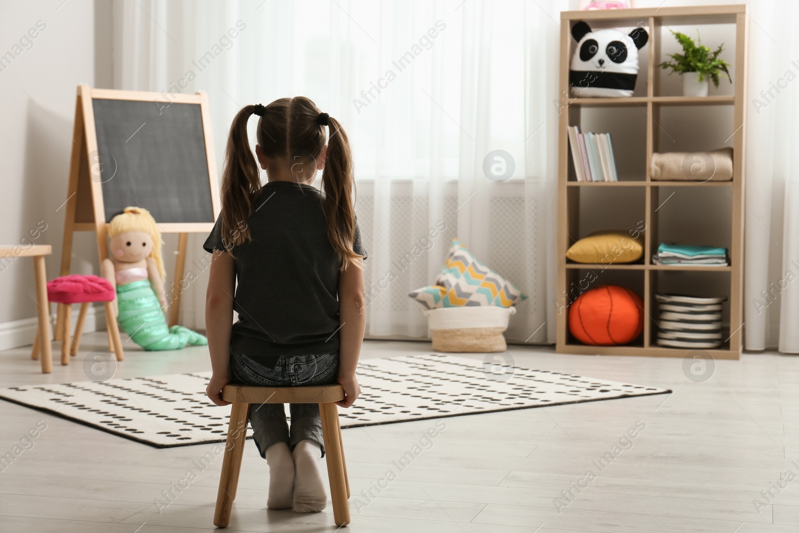 Photo of Lonely little girl at home, back view. Autism concept