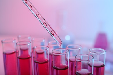 Photo of Dripping reagent into test tube with red liquid, closeup. Laboratory analysis