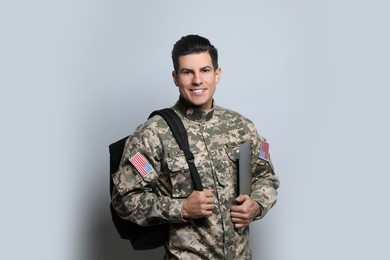 Cadet with backpack and laptop on light grey background. Military education