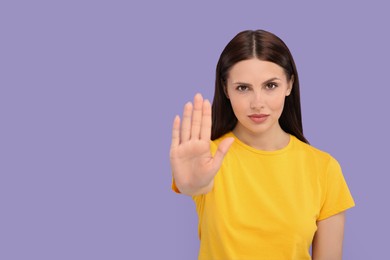 Photo of Woman showing stop gesture on violet background. Space for text