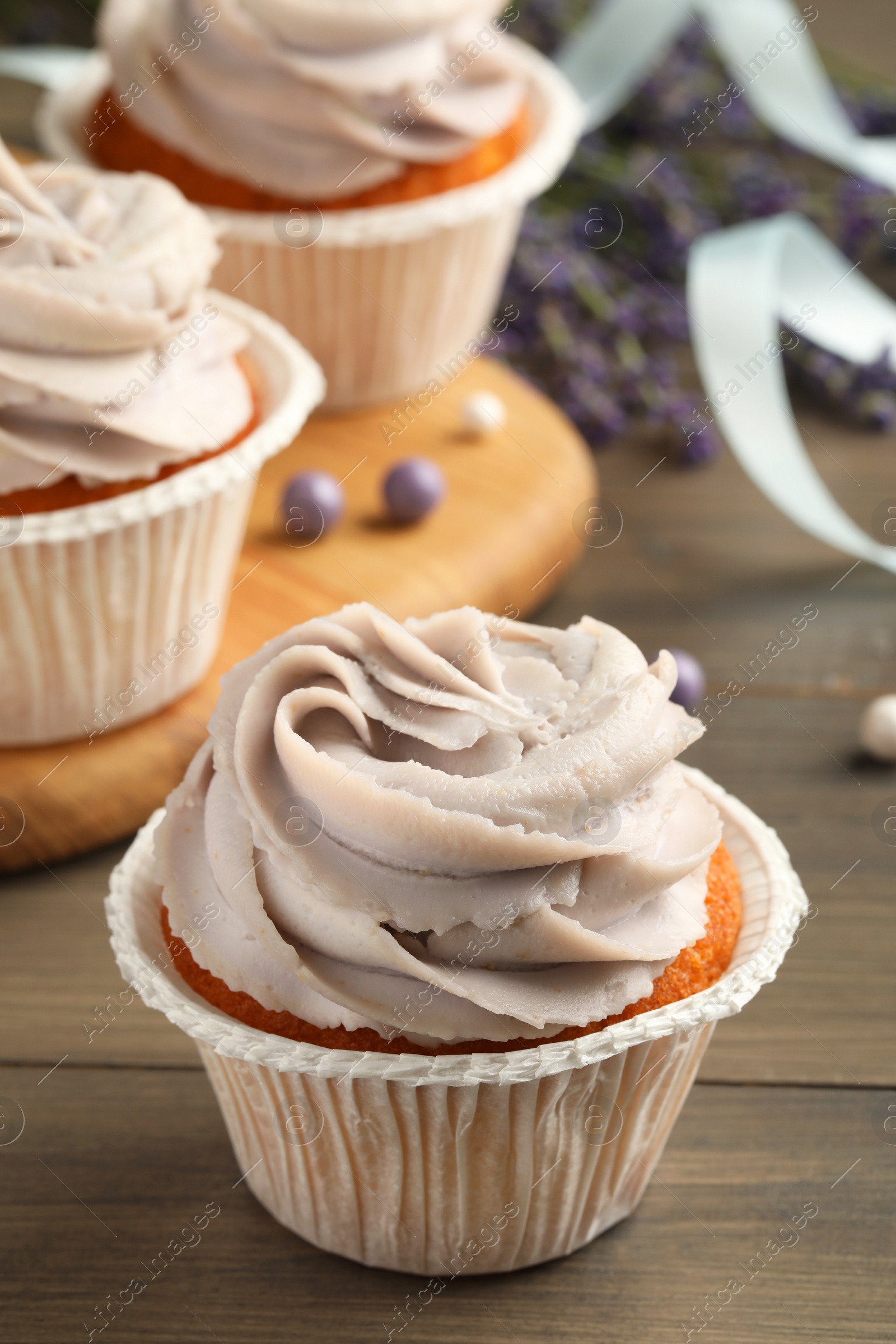 Photo of Tasty cupcakes with cream on wooden table, closeup