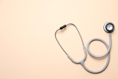 Stethoscope on beige background, top view. Space for text