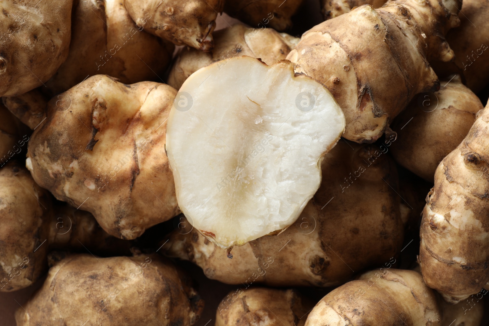 Photo of Whole and cut Jerusalem artichokes as background, top view