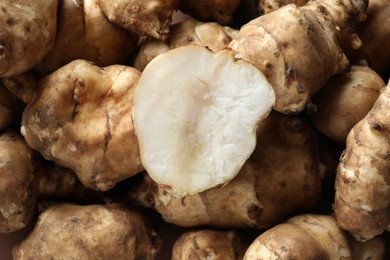 Whole and cut Jerusalem artichokes as background, top view