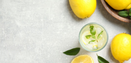 Cool freshly made lemonade and fruits on light grey table, flat lay. Space for text