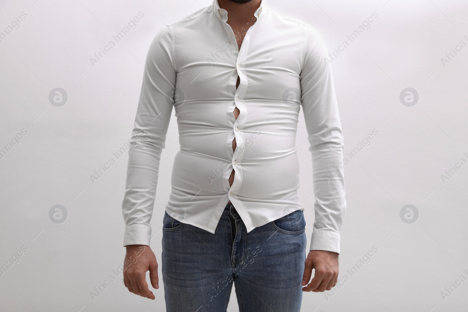 Photo of Man wearing tight shirt on white background, closeup. Overweight problem