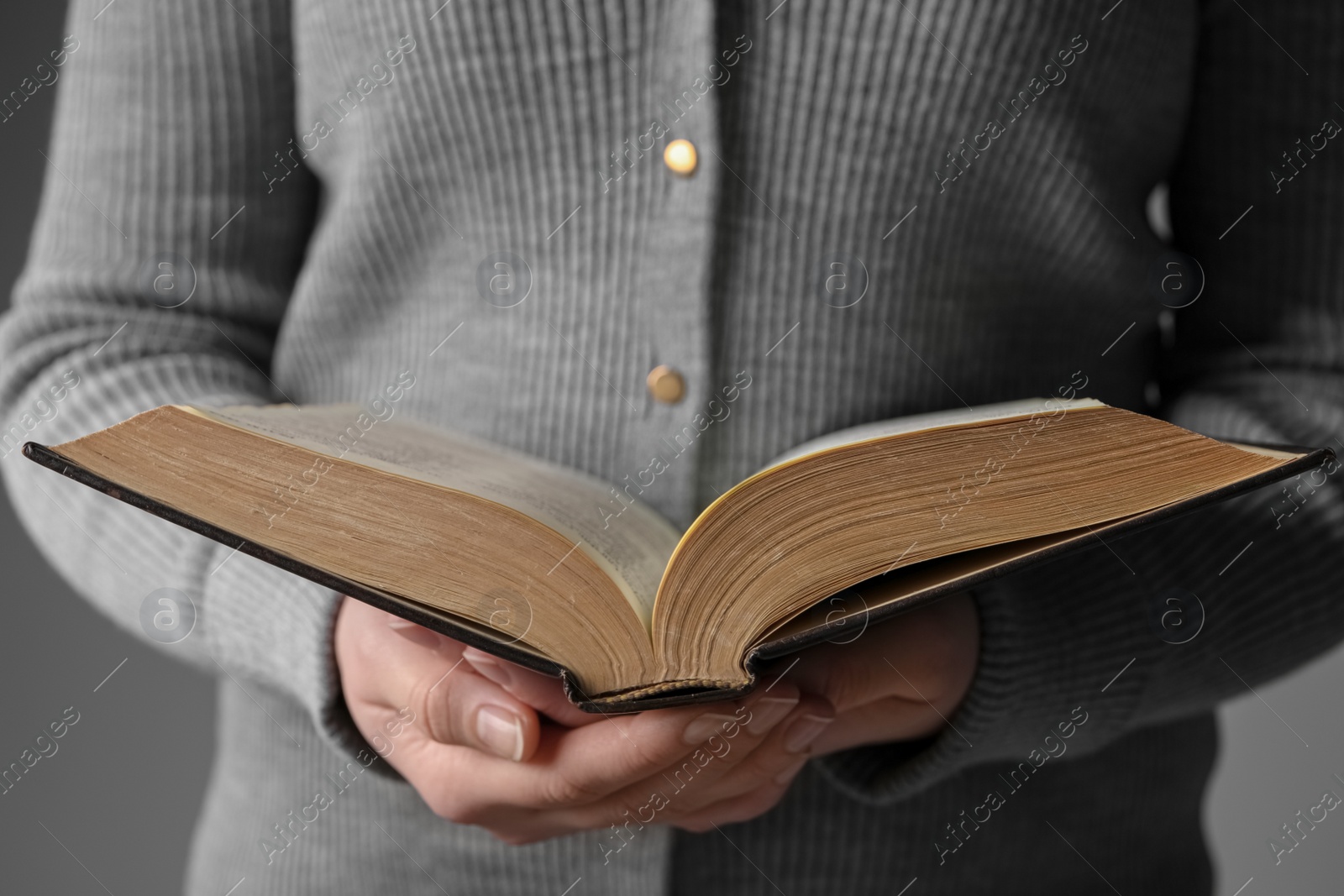 Photo of Woman reading Bible against grey background, closeup