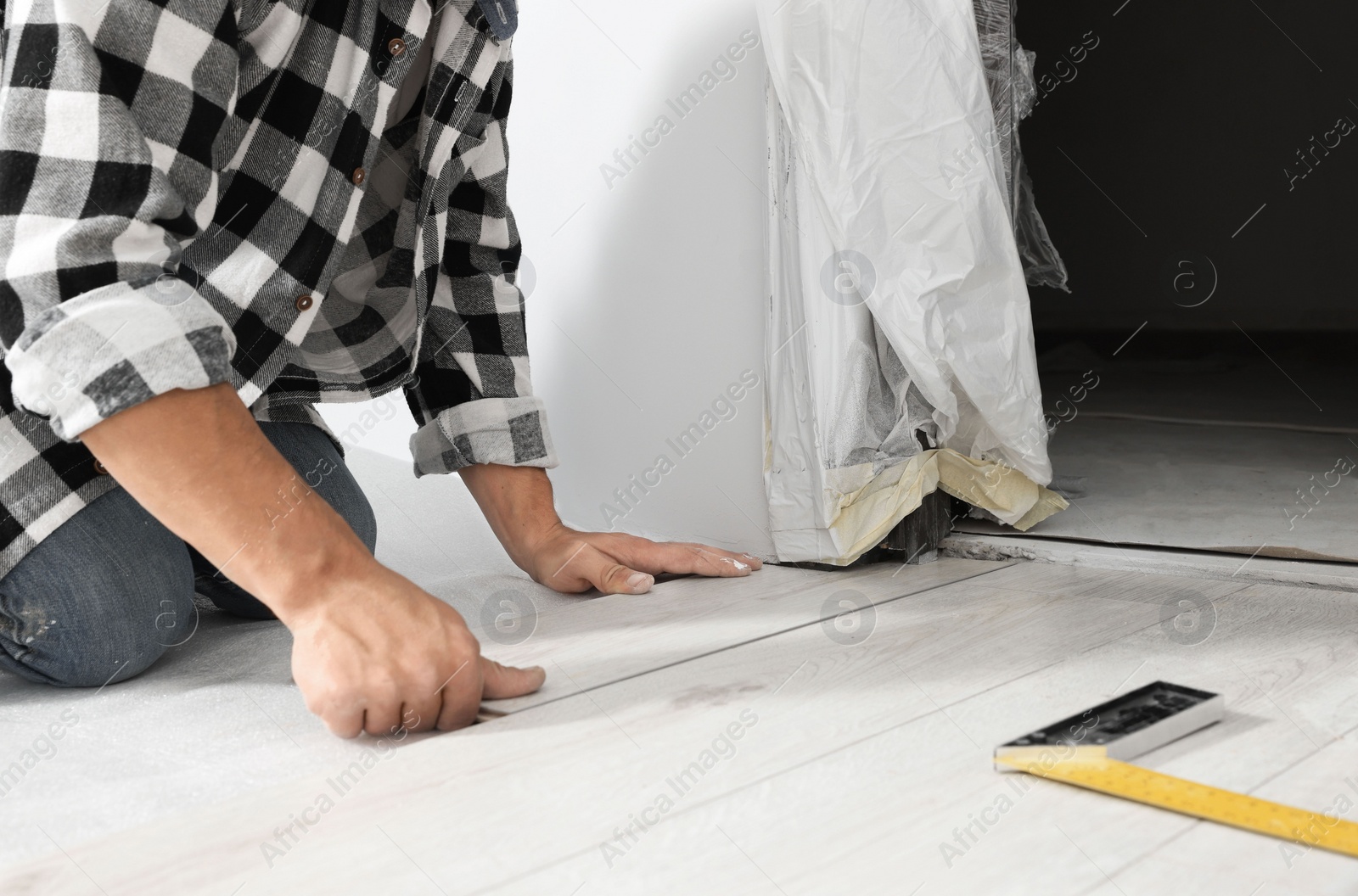 Photo of Professional worker installing new laminate flooring indoors, closeup