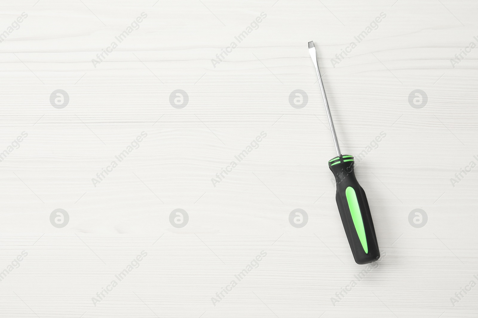 Photo of Screwdriver with black handle on white wooden table, top view. Space for text