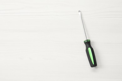 Photo of Screwdriver with black handle on white wooden table, top view. Space for text