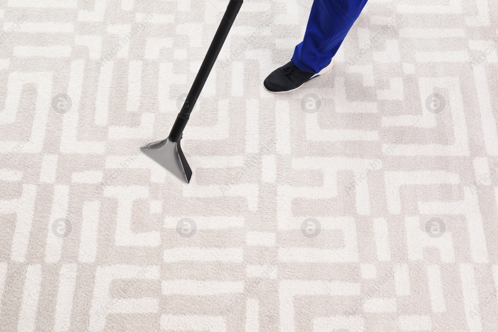 Photo of Man removing dirt from carpet with vacuum cleaner indoors, closeup. Space for text