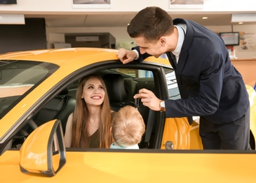 Salesman consulting young woman in car salon