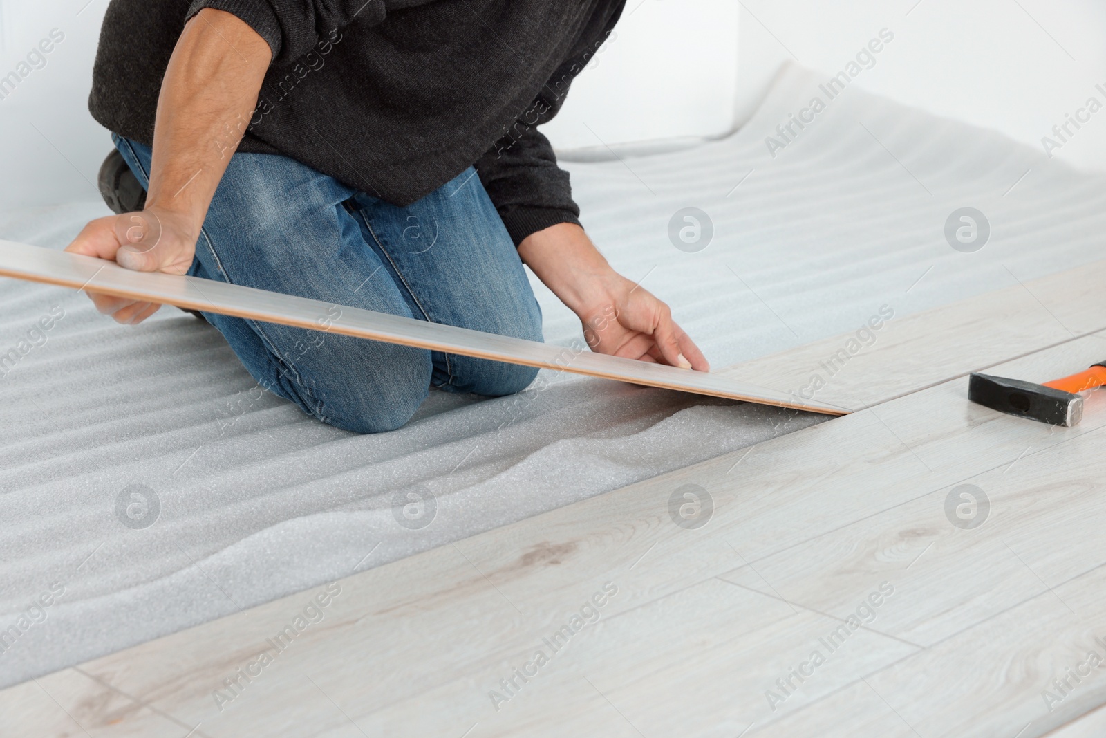 Photo of Worker installing new laminate flooring in room, closeup