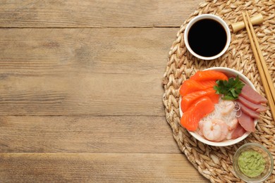 Photo of Delicious sashimi set of salmon, shrimps and tuna served with funchosa, parsley, wasabi and soy sauce on wooden table, top view. Space for text