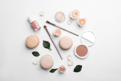 Flat lay composition with makeup products, roses and macarons on white background