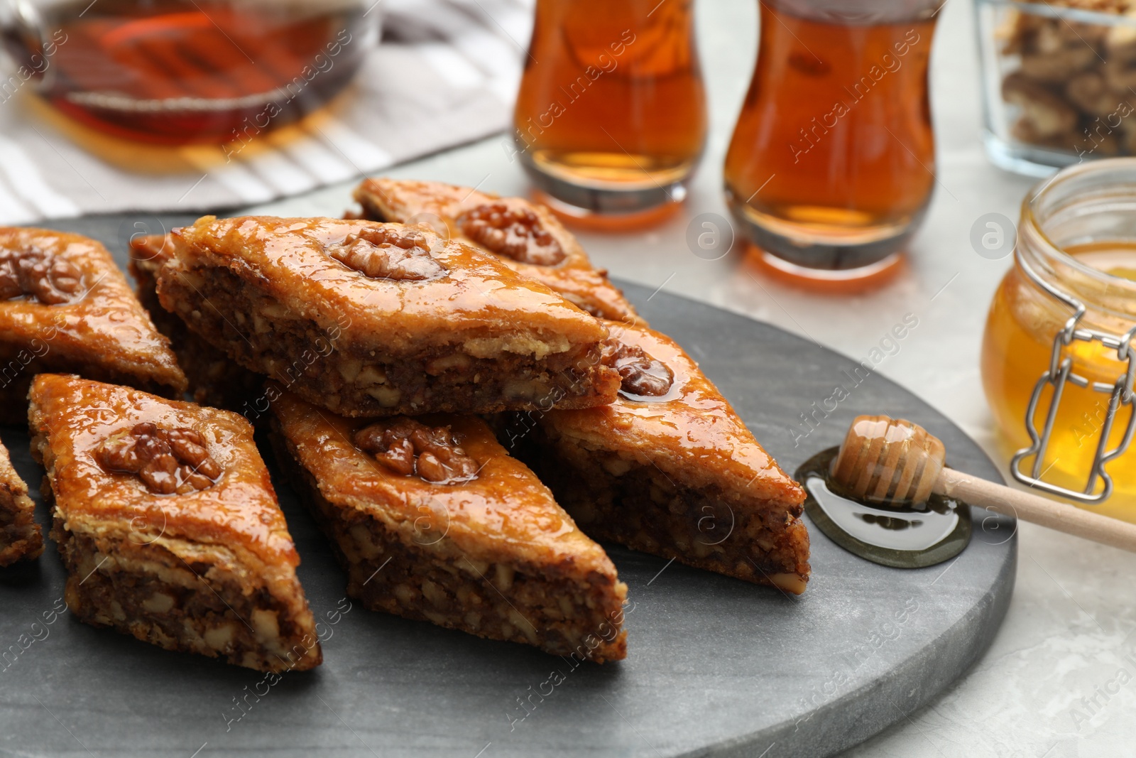 Photo of Delicious sweet baklava with walnuts on light grey table, closeup