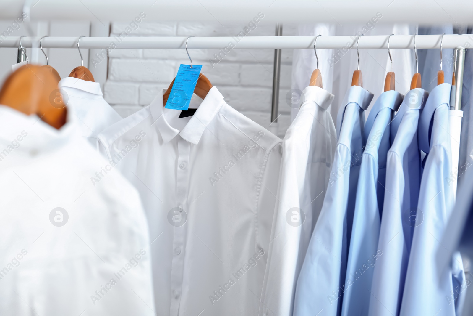 Photo of Rack with clean clothes on hangers after dry-cleaning indoors