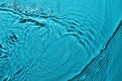 Rippled surface of clear water on light blue background, top view