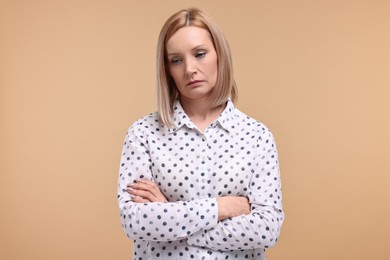 Photo of Portrait of sad woman with crossed arms on beige background