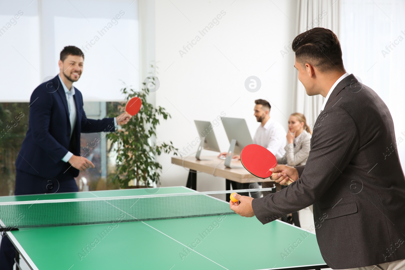 Photo of Business people playing ping pong in office