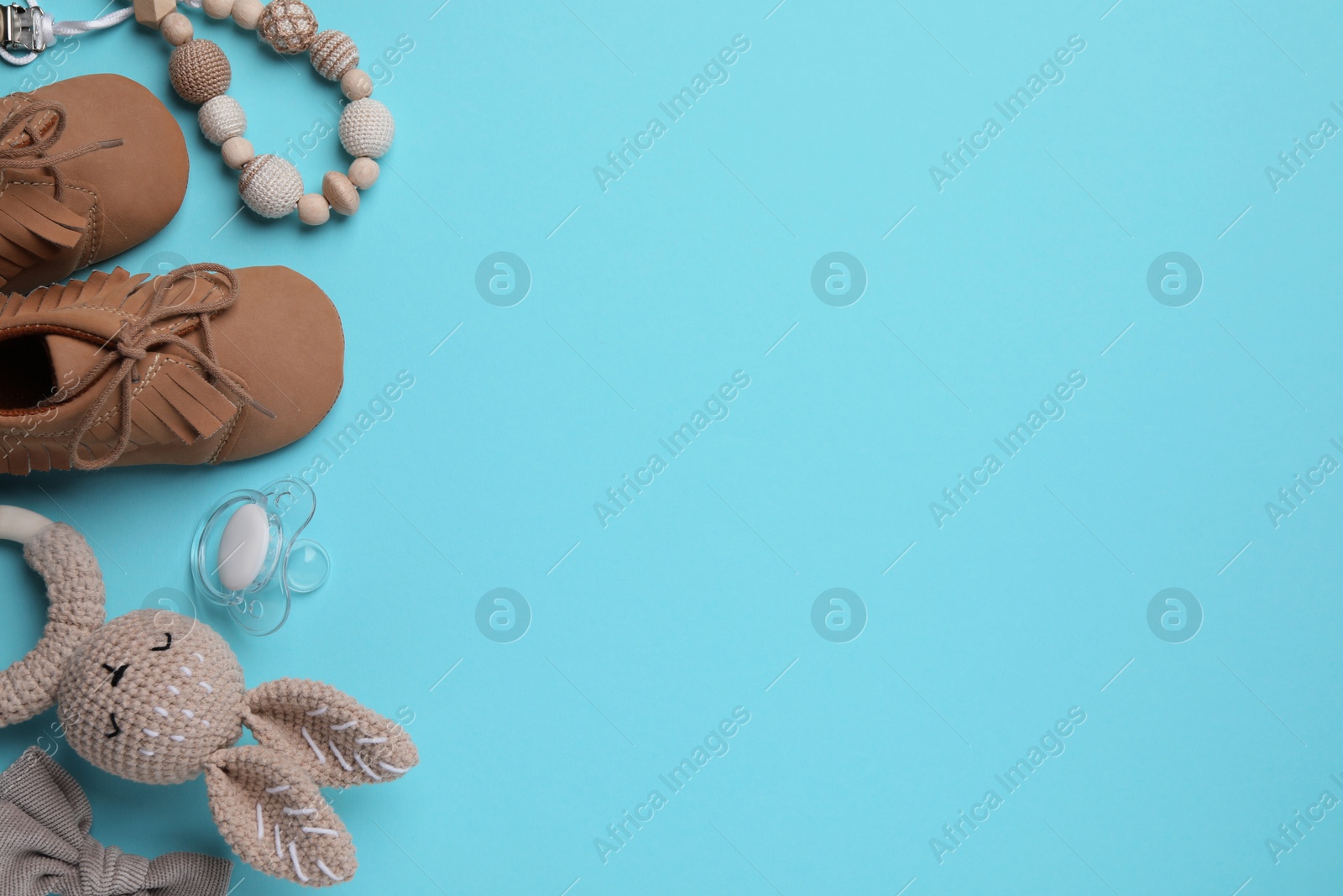 Photo of Flat lay composition with pacifier and other baby stuff on light blue background. Space for text