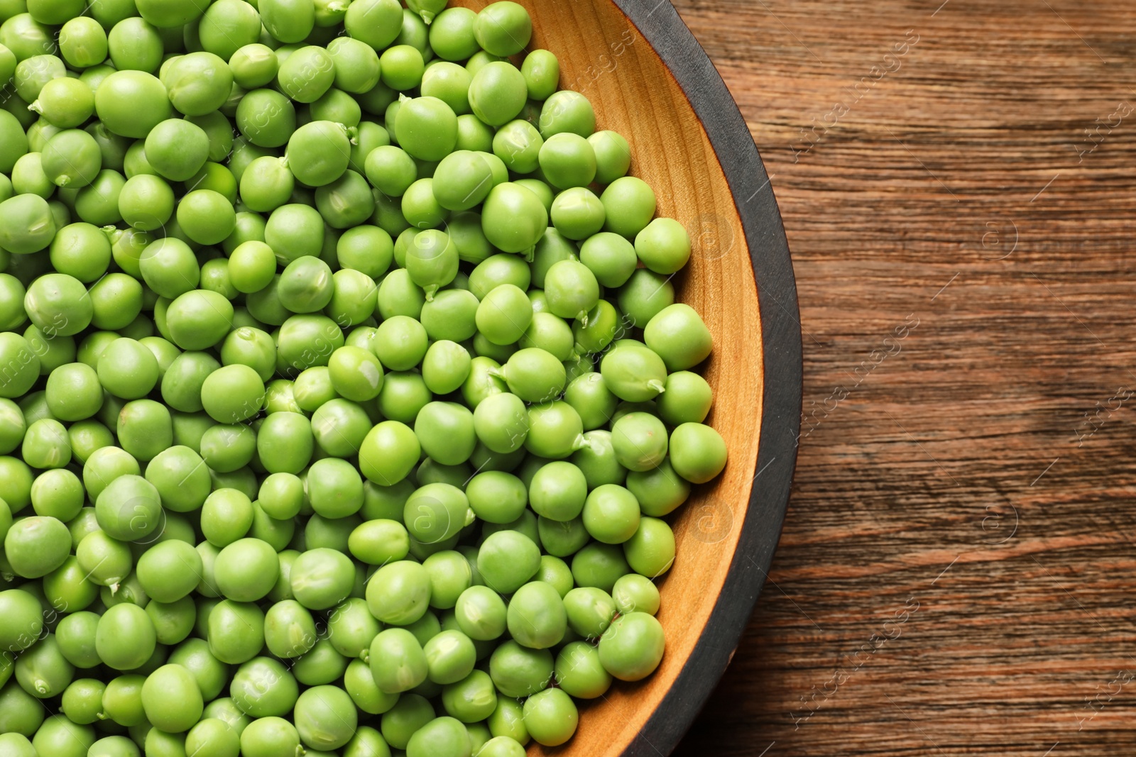 Photo of Plate with green peas on wooden background, top view