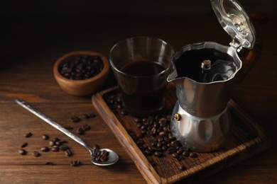Photo of Brewed coffee, moka pot and beans on wooden table, space for text