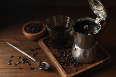 Brewed coffee, moka pot and beans on wooden table, space for text