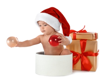 Cute little baby wearing Santa hat with Christmas gifts sitting in box on white background