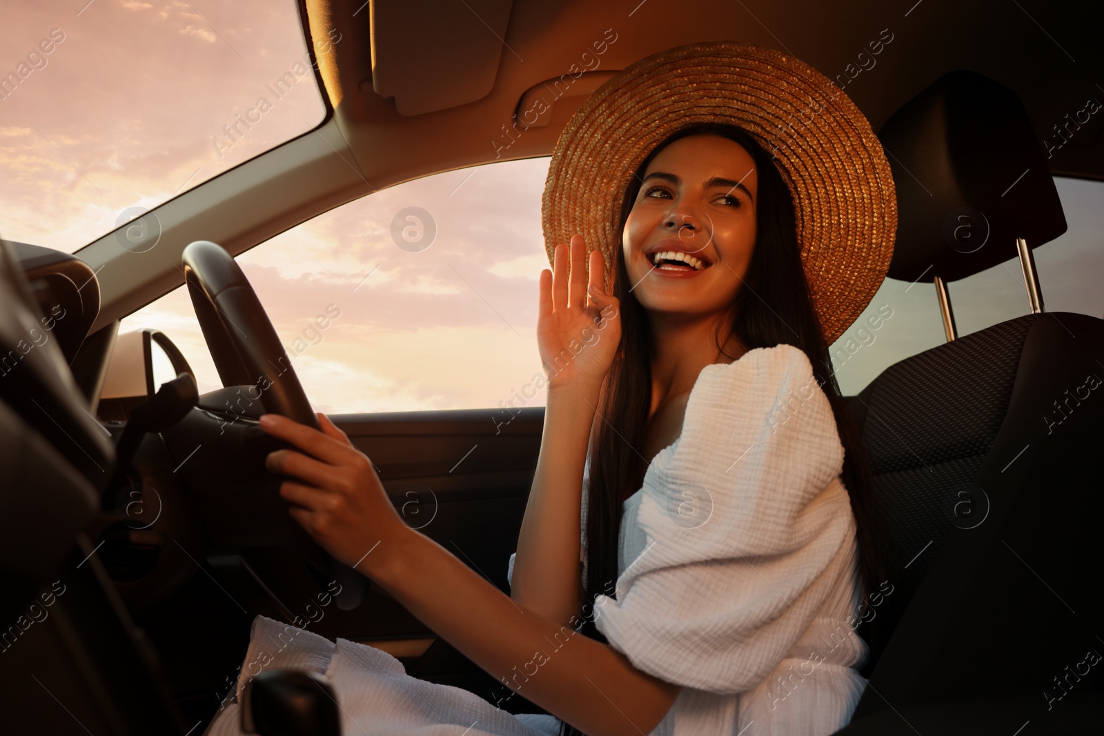 Photo of Beautiful young woman sitting in her car, low angle view. Enjoying trip