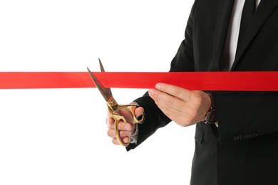 Photo of Man in office suit cutting red ribbon isolated on white, closeup